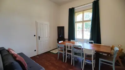 a dining room with a table and chairs and a couch at Villa Lobkovice: Gemütliches Gästehaus am Schloss in Lobkovice