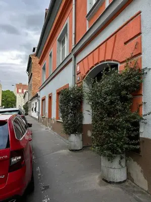 a red car parked next to a building with two plants at Pražský byt s dobrou dostupností in Prague