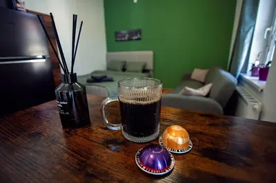 a cup of coffee on a wooden table with a vase at The Tranquil Palace in Prague