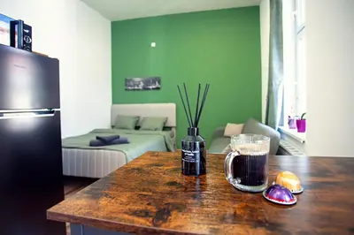 a kitchen with a refrigerator and a table with a drink at The Tranquil Palace in Prague