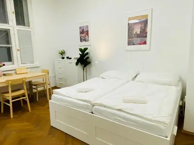 a white bedroom with a white bed and a table at Maiselova Old Town Apartment in Prague