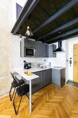 a kitchen with gray cabinets and a white table and chairs at Bohéme Apartments - Karlín in Prague