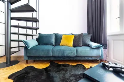 a living room with a blue couch with yellow pillows at Bohéme Apartments - Karlín in Prague