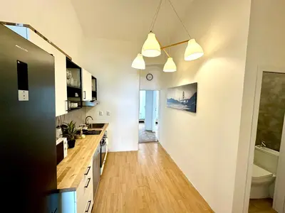 a kitchen with white walls and a wooden floor at Best location in Prague! 4 bedrooms and super host! in Prague