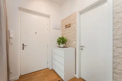 a white door in a white room with a plant on a dresser at Old Town Square Studio in Prague