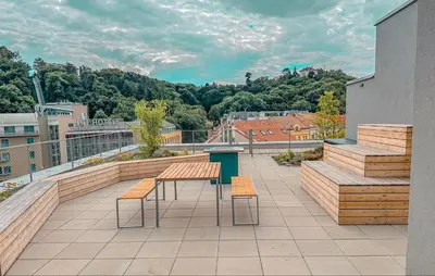 a balcony with a table and benches on a building at My Mozartova in Prague
