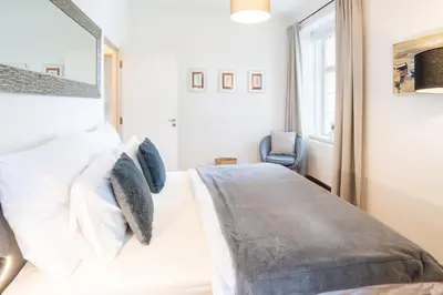 a bedroom with a white bed and a chair at River View Apartment in Prague