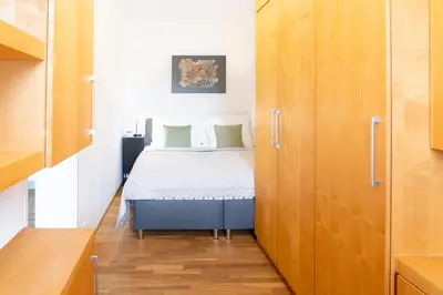 a small bedroom with a bed and wooden cabinets at River View Apartment in Prague