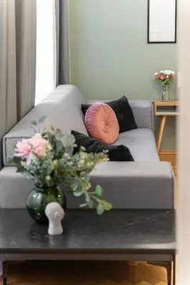 a gray couch with a vase with flowers on a table at 2# Fancy share Apartment with Own Bathroom in Prague