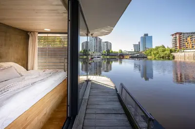 a room with a bed and a view of a river at Hausboat Holešovice in Prague