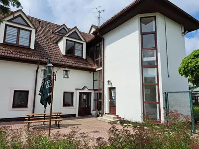 a white house with a bench in front of it at Penzion Škubánek in Mladá Boleslav