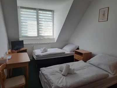 a small bedroom with two beds and a window at Penzion Škubánek in Mladá Boleslav