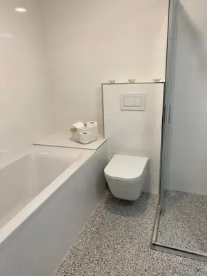 a white bathroom with a toilet and a bath tub at 2+kk se vstupem na zahradu in Prague