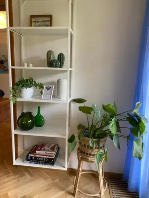 a white book shelf with plants and a chair at 2+kk se vstupem na zahradu in Prague