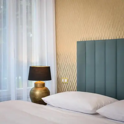 a bedroom with a bed with a lamp next to a window at PAPPAS hotel&studio in Poděbrady