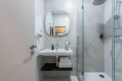 a white bathroom with a sink and a mirror at PAPPAS hotel&studio in Poděbrady