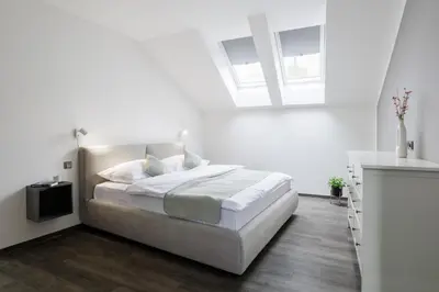 a white bedroom with a bed and a window at River Apartments in Mladá Boleslav