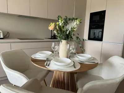 a table with white chairs and a vase with flowers at Rentero NEW Modern, River View APT near Prague City Center in Prague