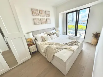 a white bedroom with a bed and a window at Rentero NEW Modern, River View APT near Prague City Center in Prague