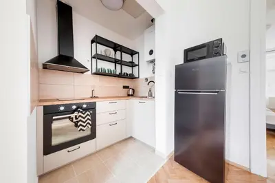 a kitchen with a stainless steel refrigerator and white cabinets at City center premium apartment Bohemia in Prague