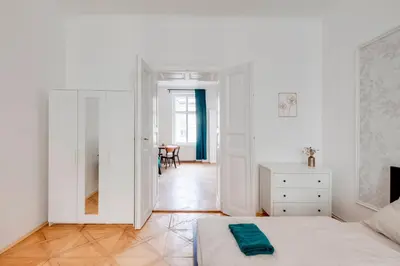 a white bedroom with a bed and a table at City center premium apartment Bohemia in Prague