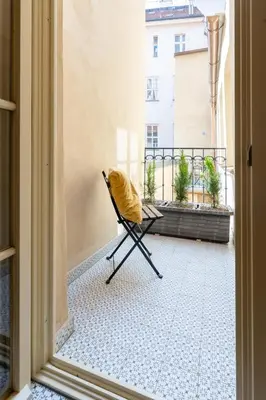 a chair with a yellow blanket sitting on a balcony at Prague Days - Two-bedroom Apartment with Workspace and Balcony in Old Town in Prague