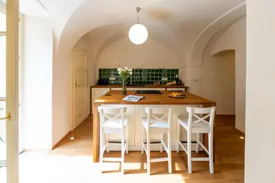 a kitchen with a wooden table and white chairs at Prague Days - Two-bedroom Apartment with Workspace and Balcony in Old Town in Prague