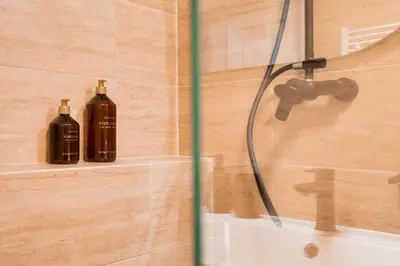 two bottles of soap are sitting on a shelf in a shower at City center premium apartment in Prague