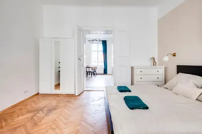 a white bedroom with a bed and a table at City center premium apartment in Prague