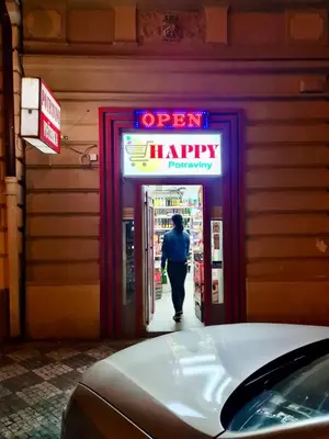 a man walking into a shop with a neon happy sign at Modern Spacious Apartment in center Prague in Prague