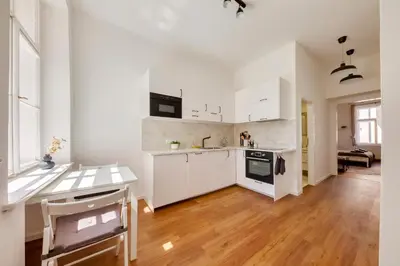 a kitchen with white cabinets and a wooden floor at Premium Apartment Nearby Centre in Prague