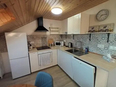 a kitchen with white cabinets and a clock on the wall at Apartmán Svaté Pole in Svaté Pole