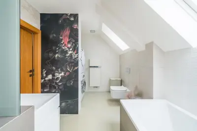 a bathroom with a toilet and a wall with a painting at Apartmán VALORI - 100m2 in Poděbrady