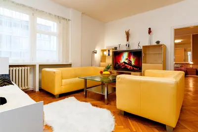 a living room with yellow furniture and a tv at Moonlight Deluxe Suite in Prague