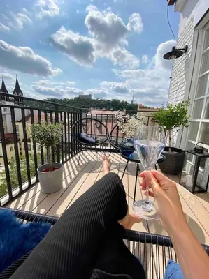 a woman sitting on a balcony with a wine glass at Romantic Terrace Studio in Karlín in Prague
