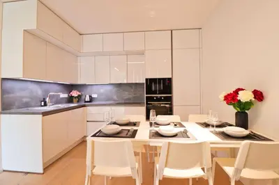 a white kitchen with a table and chairs at The Peony Apartment in Smichov, Prague 5 in Prague