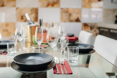 a table with glasses and plates and forks and wine glasses at City View Luxury Apartments with Foosball & Xbox - In City Centre in Prague