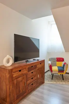 a living room with a flat screen tv and a chair at Rybna - Old Town Residence in Prague