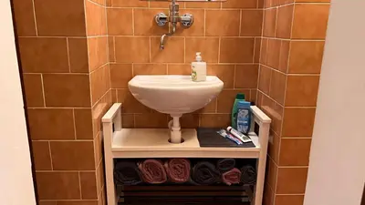 a bathroom with a sink and a shelf with towels at Prague Castle Garden Residence in Prague