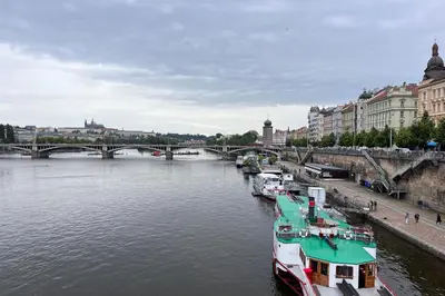 a group of boats docked in a river with a bridge at Comfortable and cosy apt a few steps from Dancing House and Naplavka Dance in Prague