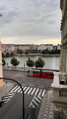 a red train on a street next to a river at Comfortable and cosy apt a few steps from Dancing House and Naplavka Dance in Prague