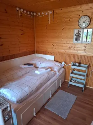 a bed in a room with a clock on the wall at Záhradní chata Kbelská 335 in Prague