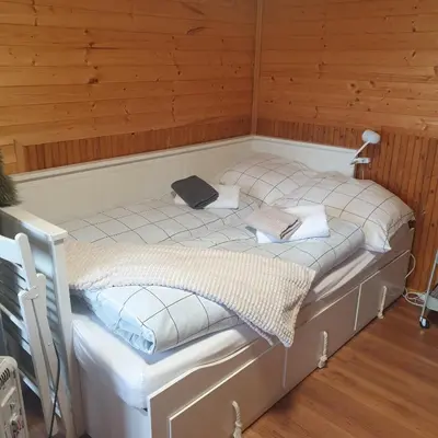 a small bed in a room with wooden walls at Záhradní chata Kbelská 335 in Prague