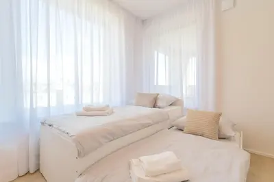 a white room with two beds and a window at Bright 2BR - 8th floor, Balcony, Free Parking - by Gravity Prague in Prague