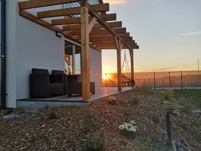 a pergola on a house with the sunset in the background at Apartman Amanda - Ohrada in Choťánky