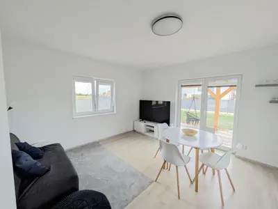 a white bathroom with a toilet and a window at Apartman Amanda - Ohrada in Choťánky