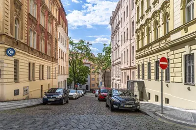a street with cars parked on a cobblestone street at Apartment Charkovska 18 in Prague
