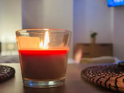 a candle in a glass sitting on a table at Útulný apartmán v klidné části Benešova in Benešov