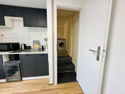 a stairway leading to a kitchen with black cabinets at Útulný apartmán v klidné části Benešova in Benešov