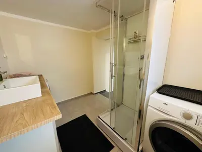 a bathroom with a shower and a washing machine at Útulný apartmán v klidné části Benešova in Benešov